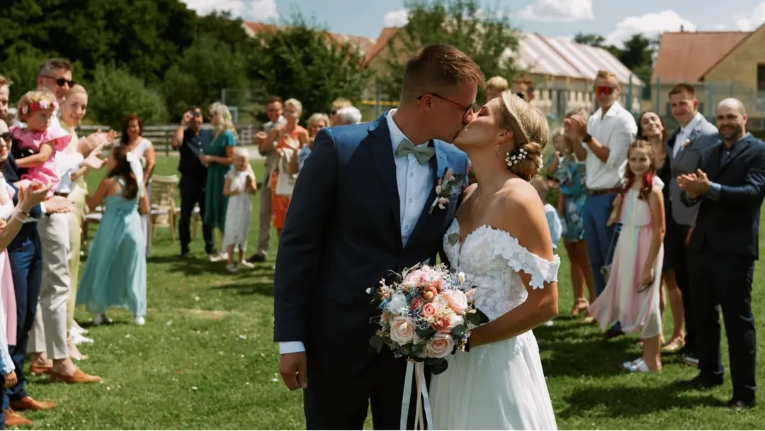 Ženich a nevěsta se líbají při obřadu mezi tleskajícími hosty